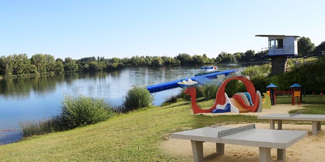 See mit Spielplatz und Tischtennisplatte im Vordergrund.