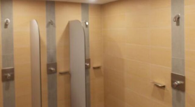 Duschkabinen im Schwimmbad mit gelben Fliesen.