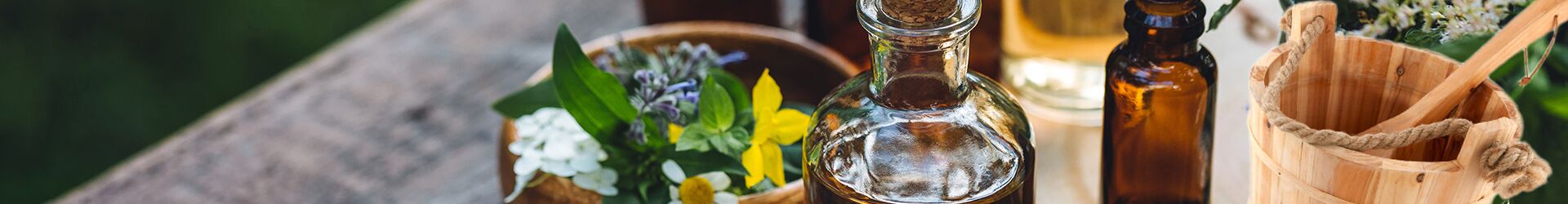 Natürliche Pflegeprodukte in Flaschen mit Blumen und Holzaccessoires.