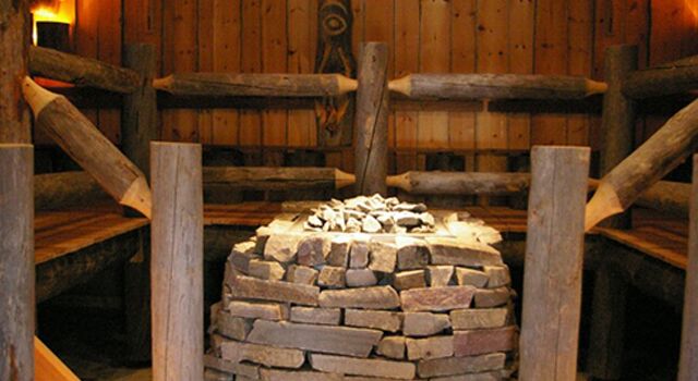 Traditionelle Sauna aus Holz mit Steinaufgussofen in der Mitte