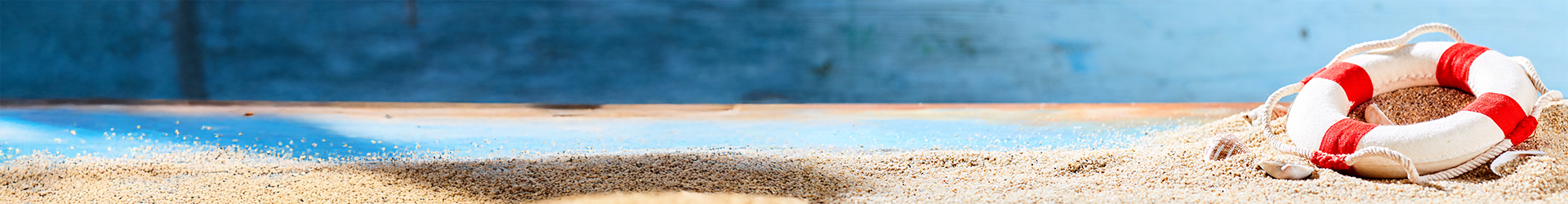 Rettungsring auf Sand vor blauem Hintergrund.
