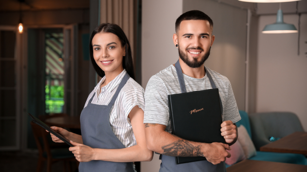 Zwei Kellner stehen in einem Restaurant mit Speisekarten.