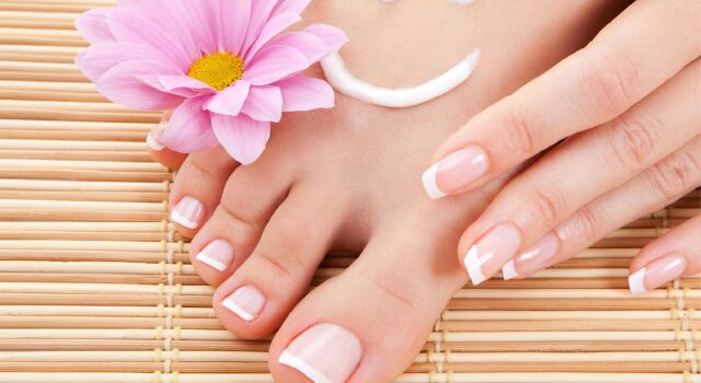 Fuß mit Blume und Creme-Lächeln auf Bambusmatte, gepflegte Nägel.