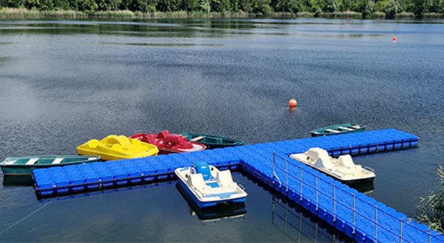 Tretboote am schwimmenden Steg auf einem See bei sonnigem Wetter.