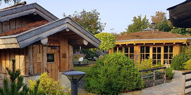 Holzhäuser und Garten im Freien bei sonnigem Wetter.