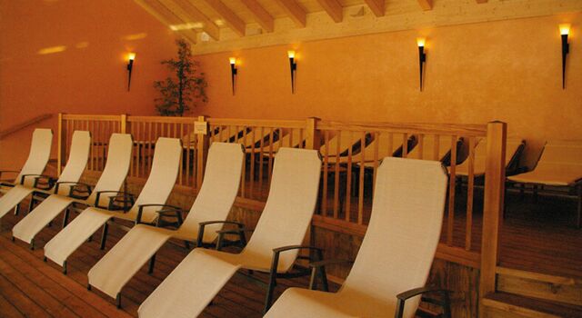 Leere Liegestühle in einem warm beleuchteten Ruheraum mit Holzboden.