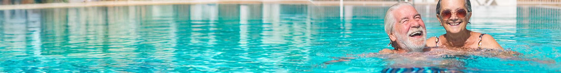 Lachendes Paar schwimmt im Schwimmbad, entspannte Atmosphäre.