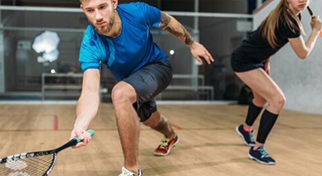 Zwei Personen spielen Squash in einem Squashcourt