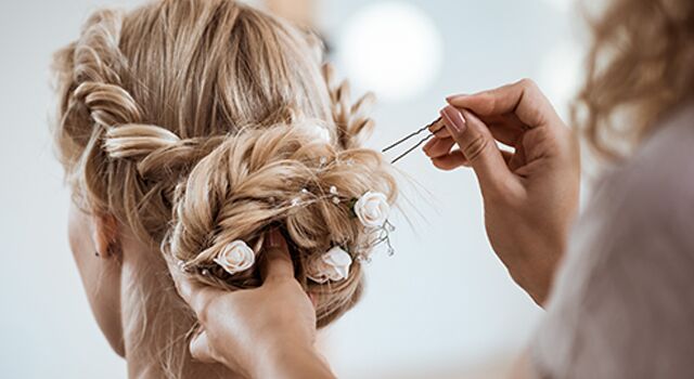 Haare werden zu einer Hochsteckfrisur mit Blumen gesteckt.
