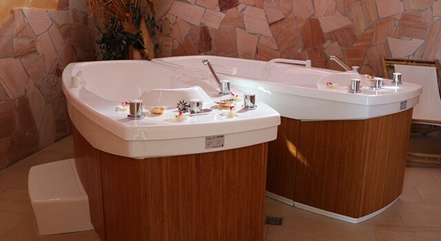 Zwei moderne Whirlpools in einem Raum mit Steinwand.