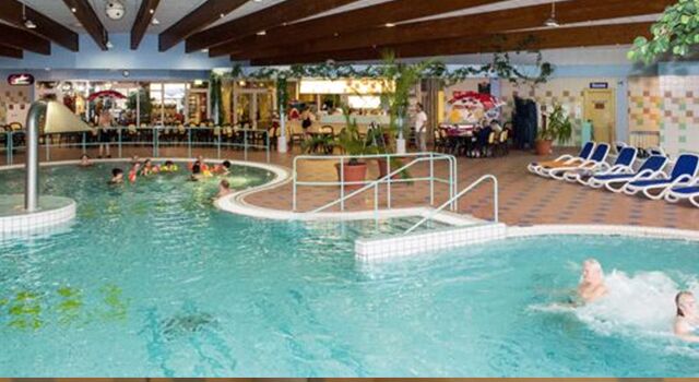 Erlebnisbad mit Schwimmern und Liegestühlen am Rand.